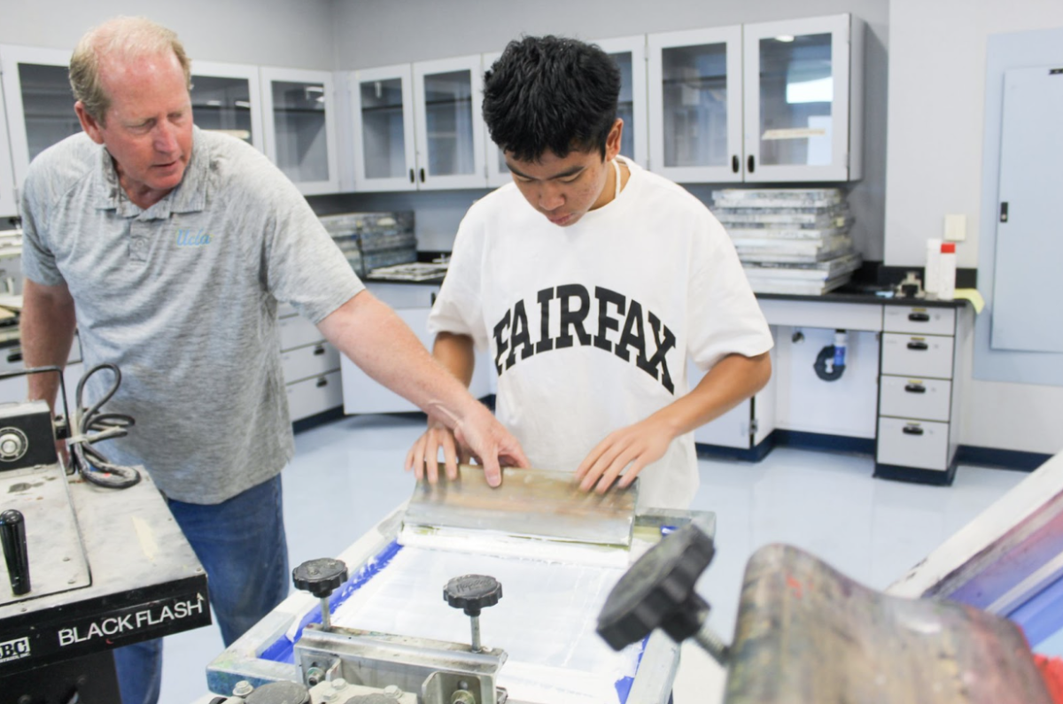 INKING IT IN: Junior Nathan Tuason carefully transfers his design onto a shirt, guided by screenprinting teacher Robert Stuart.